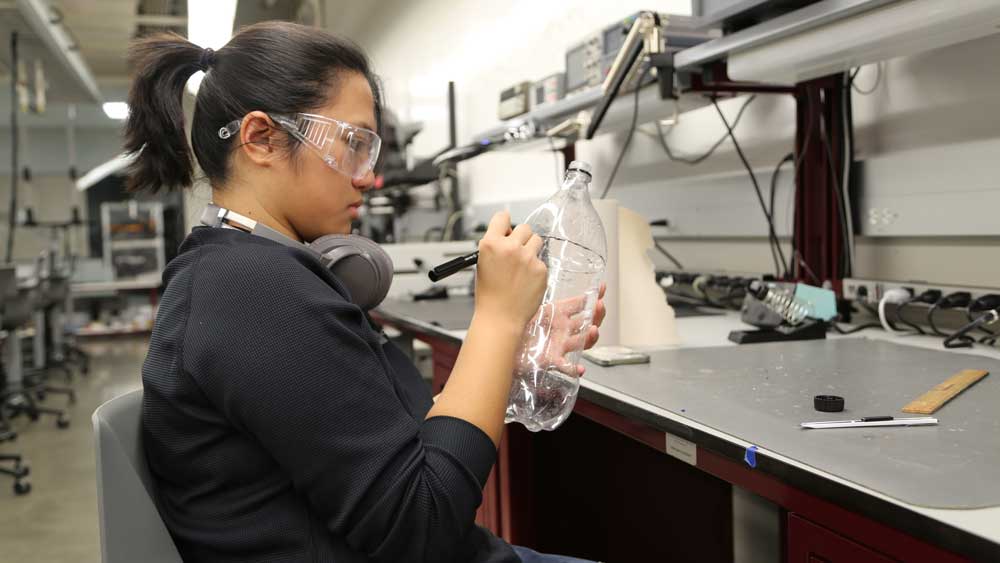 A student in safety glasses making a prototype at the Fischer Engineering Design Center
